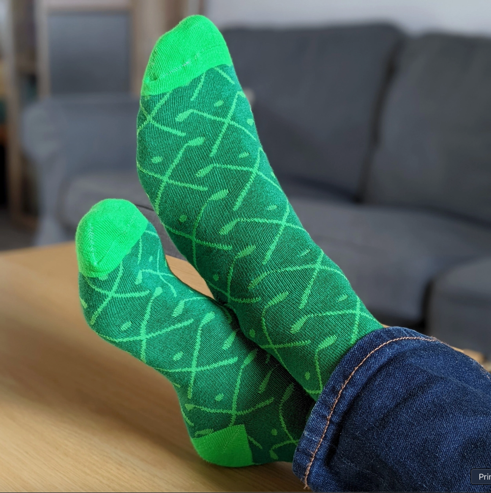 Green patterned socks worn by a person sitting on a couch.