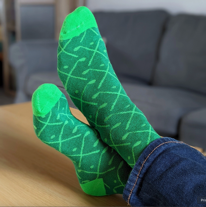 Green patterned socks worn by a person sitting on a couch.