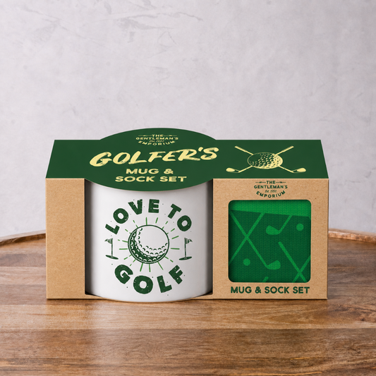 Golfer's mug and sock set in packaging on a wooden surface with a gray background