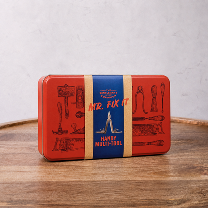 Red and blue tin box labeled 'Mr. Fix It' on a wooden surface with a white background