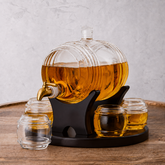 Glass liquor decanter with a gold faucet on a wooden table, filled with amber liquid.