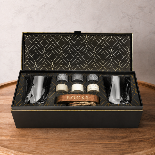 Open black gift box with decorative interior, containing bottles and a spoon on a wooden surface.
