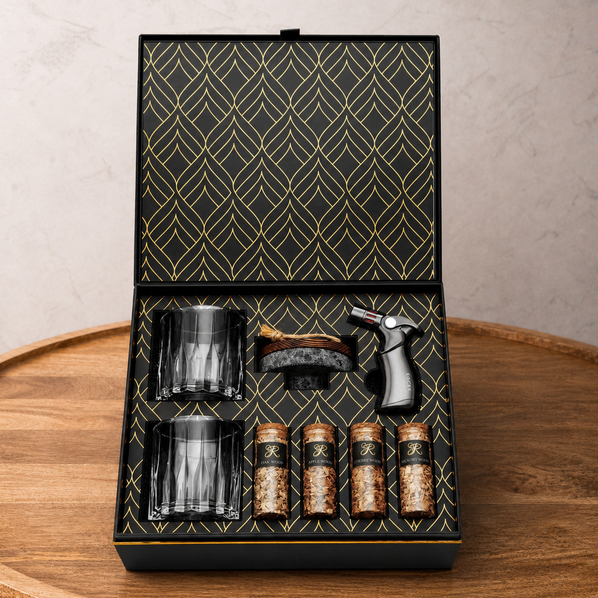 Set of glass tumblers, a brush, and bottles in a decorative box on a wooden surface.